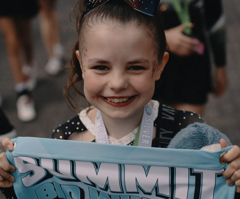 Junge Sharks-Cheerleaderin freut sich über ihre Medaille und ihr Summit Bid